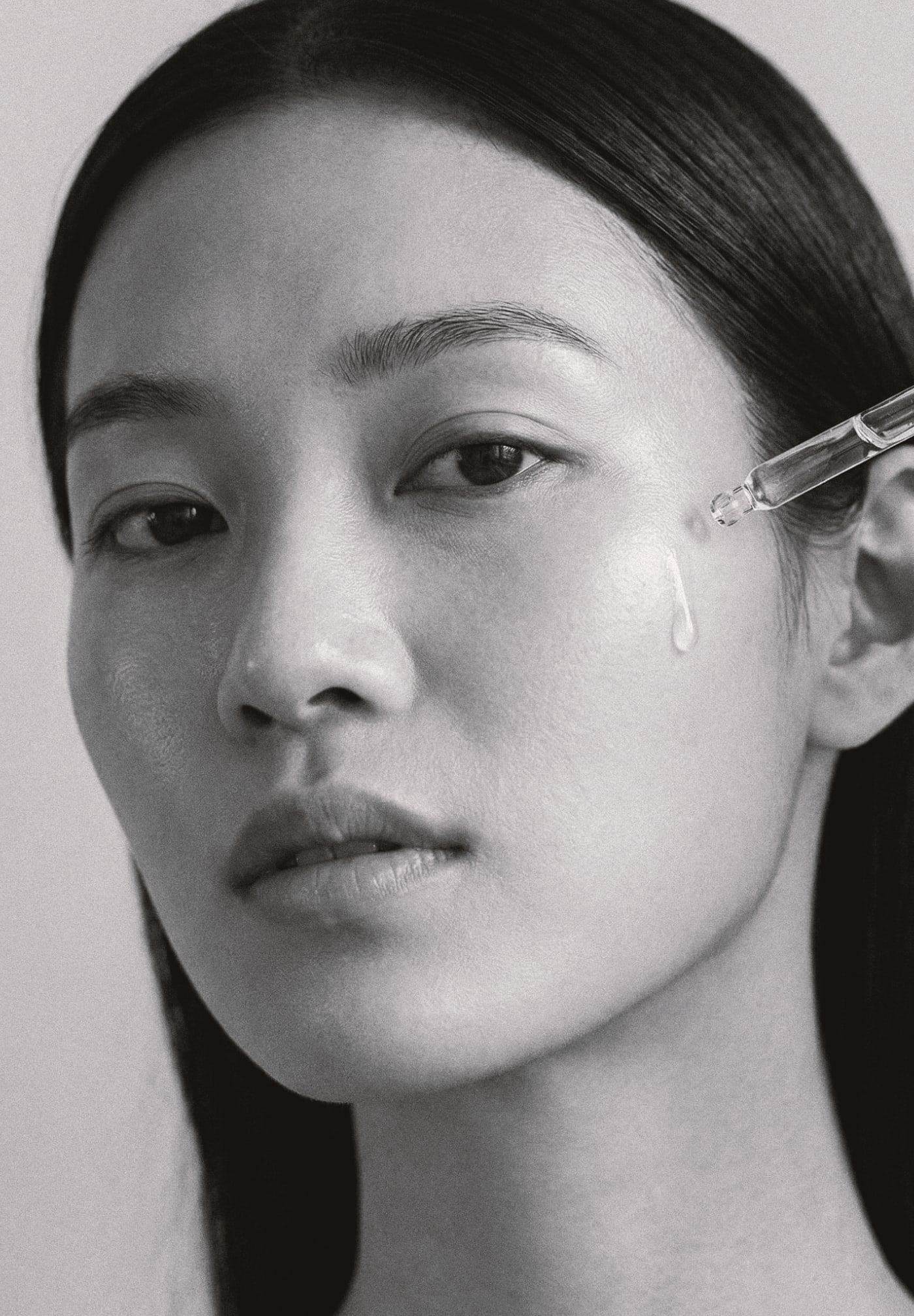 Premium K-beauty campaign photography and intentional digital commerce assets showcasing a female model applying skincare serum with a pipette dropper