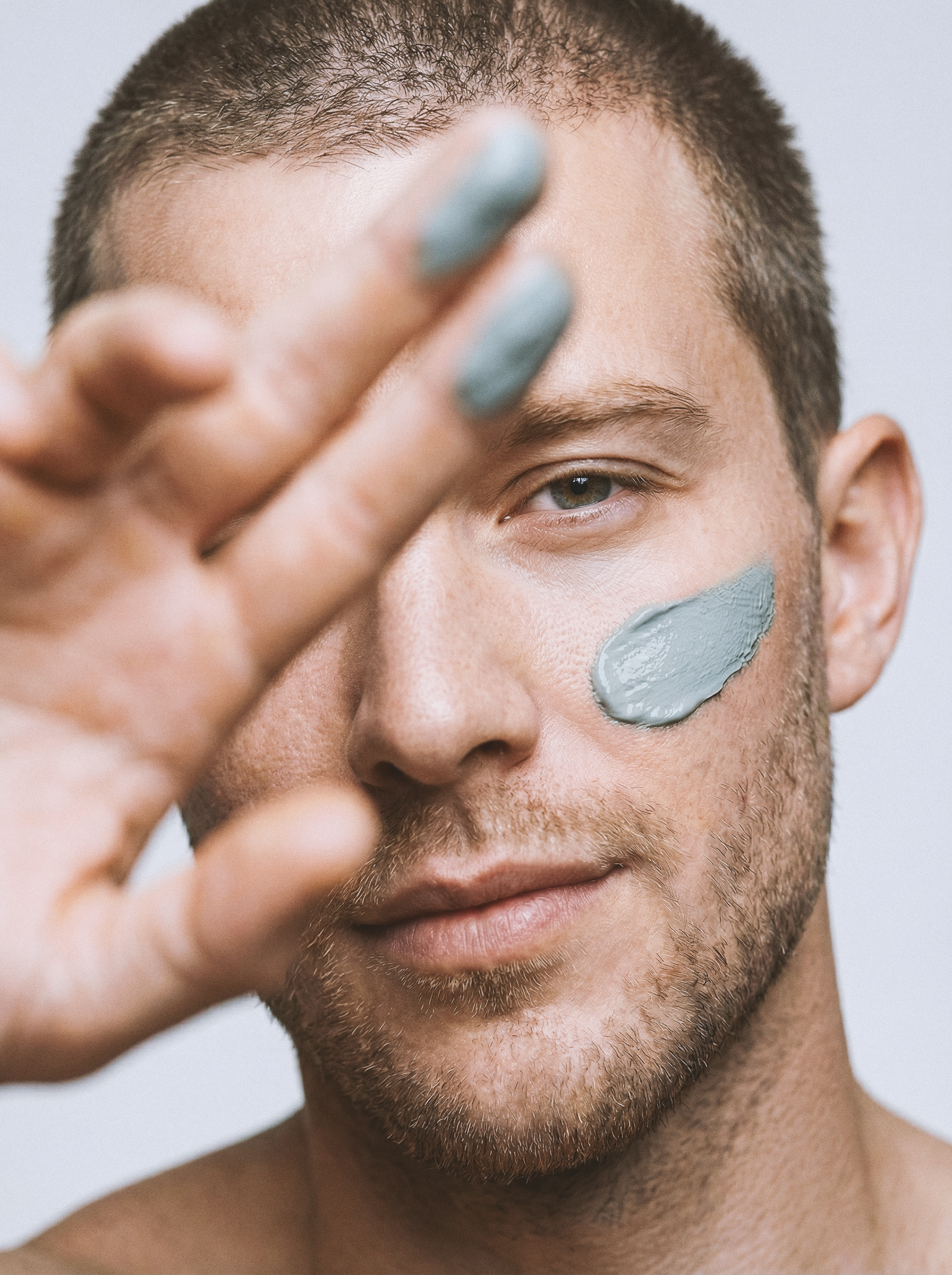 Unisex beauty campaign photography and premium launch imagery showcasing a male model applying a mineral clay mask for a skincare brand