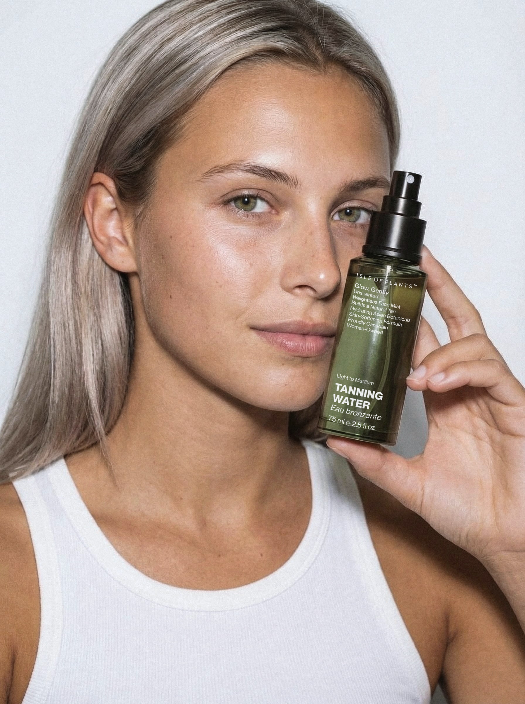 Premium beauty campaign photography and cosmetic packaging design showcasing a model holding a self-tanning water bottle for Isle of Plants